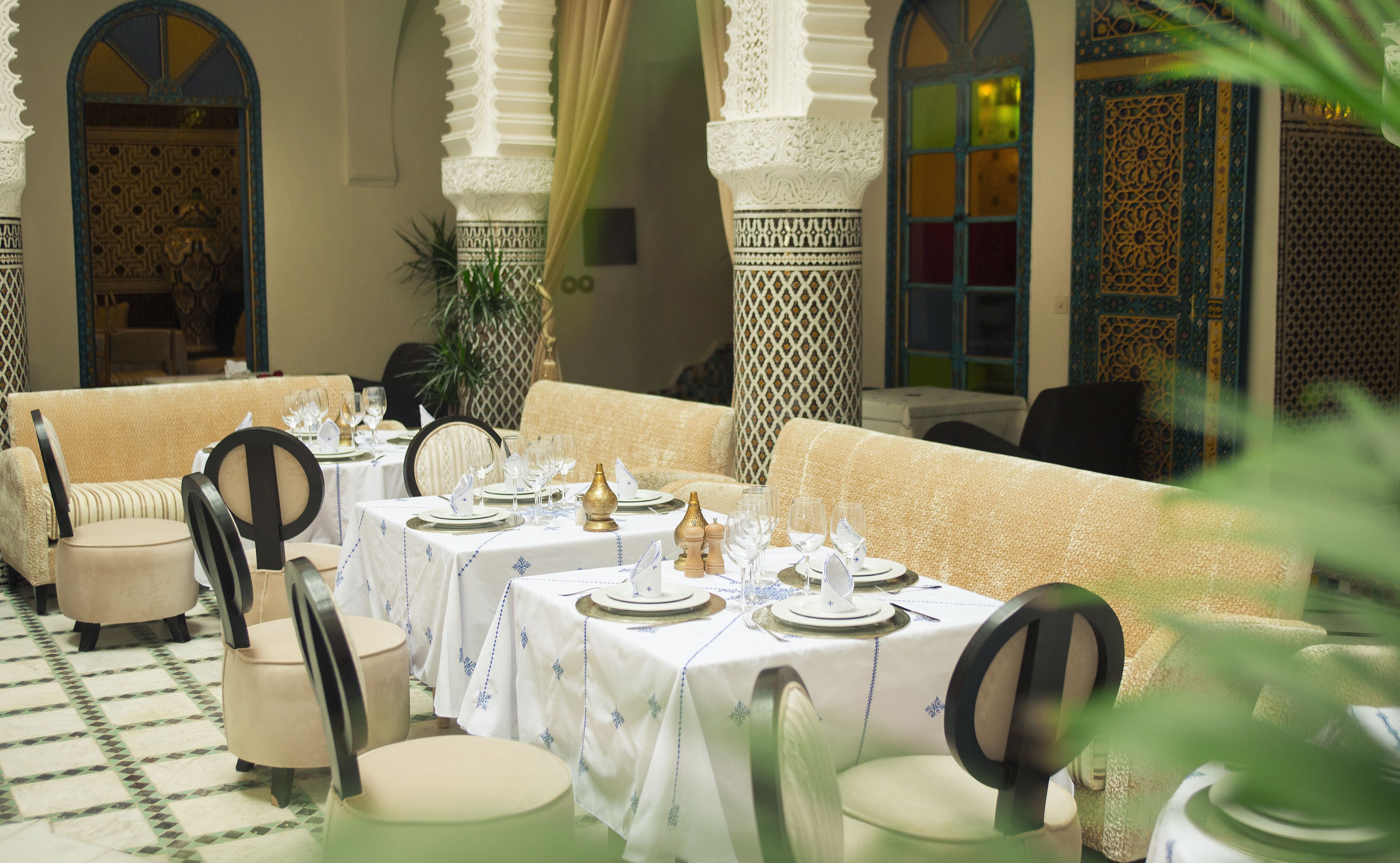 A dining area with tables set for a meal, featuring traditional Moroccan decor.