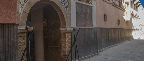 Fachada de edificio con un arco ornamentado y un letrero que dice 'PALAIOS'.
