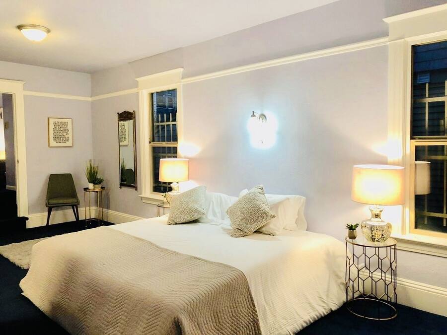 A hotel room with a large bed, two bedside lamps, a chair, and a small table with a plant.