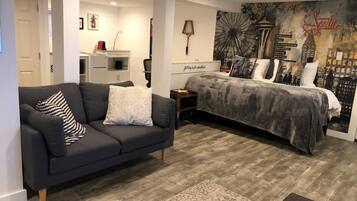 A modern bedroom with a bed, a sofa, and a city-themed wall mural.