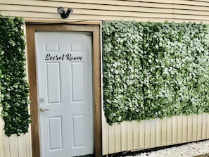 A door labeled "Secret Room" with a white door and a wall covered in green foliage. - The ART INN Seattle (Seattle)