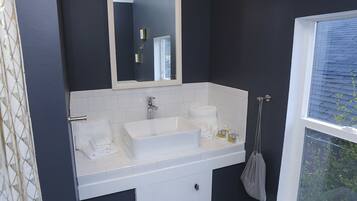 Un baño con un lavabo blanco, un espejo y una ventana.