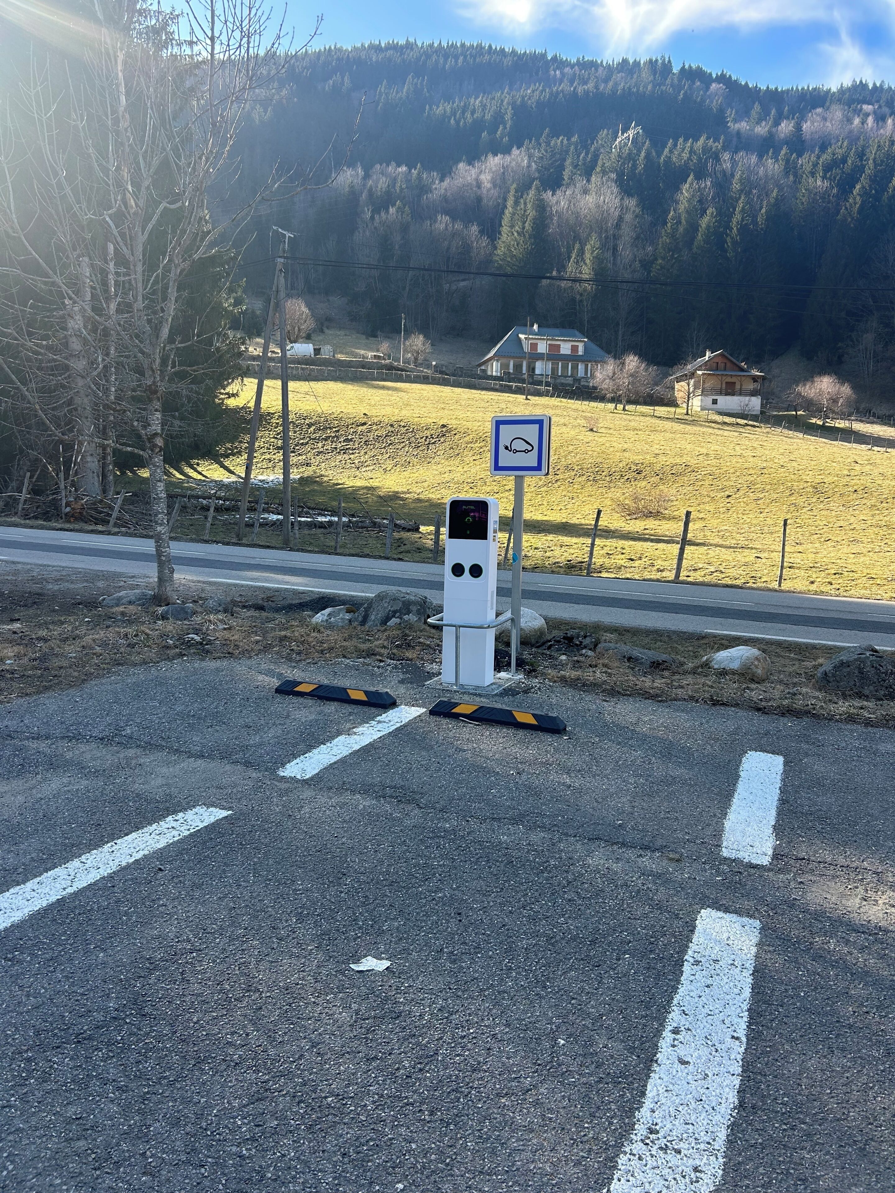 Een parkeerplaats met een laadstation, een richtingsbord en een gebouw op de achtergrond.