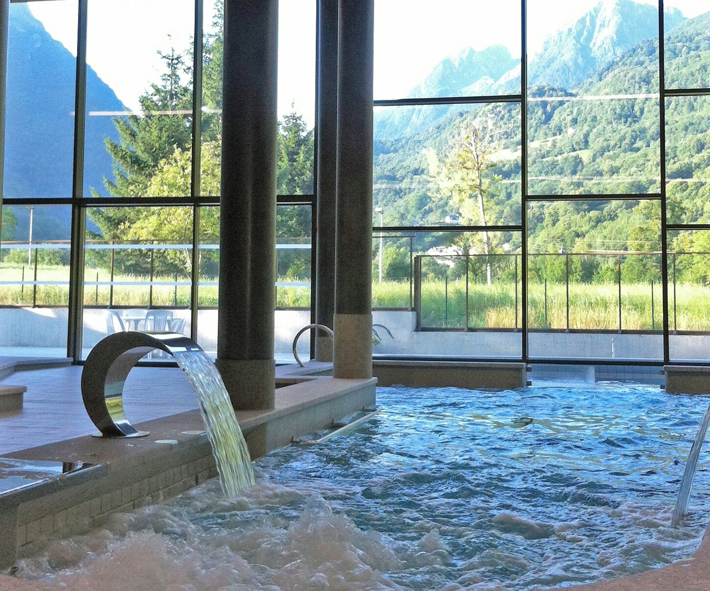 A hot spring area with a view of mountains through large windows.
