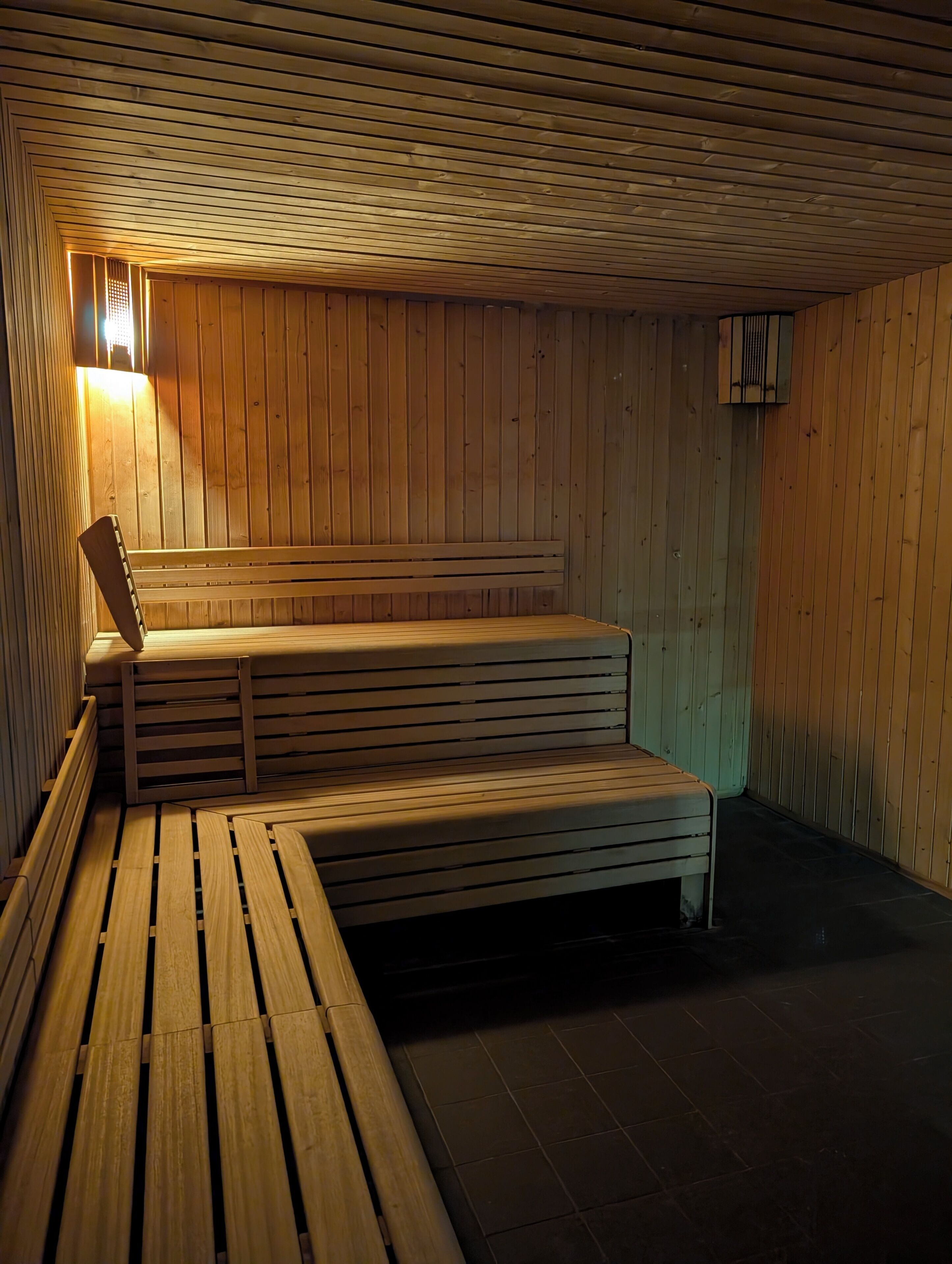 Un sauna avec des bancs en bois et un plancher incliné.