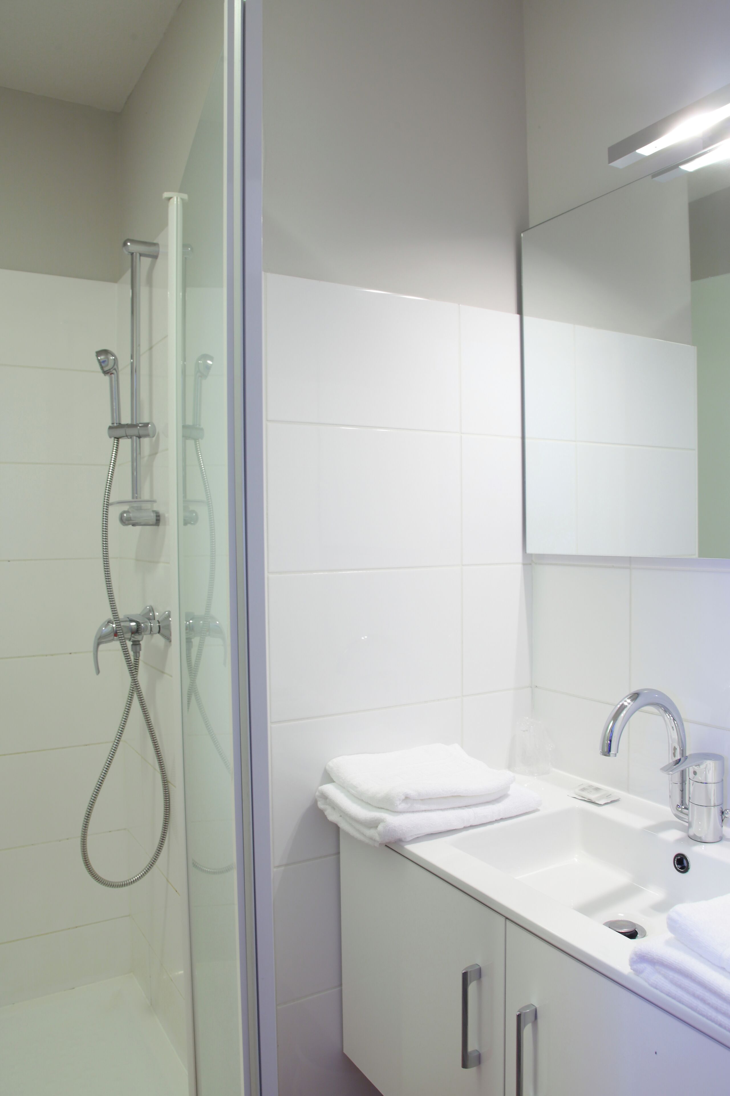 Un baño moderno con cabina de ducha de vidrio, un lavabo blanco y un espejo sobre el lavabo.
