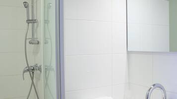 Un baño moderno con cabina de ducha de vidrio, un lavabo blanco y un espejo sobre el lavabo.