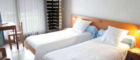 A hotel room with two beds, a desk, and a chair.