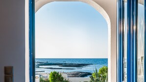Una vista a través d'una porta oberta cap a un balcó amb vista al mar.