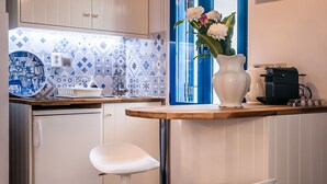 Una cuina moderna amb armaris blancs, un mosaic de fons blau i blanc, un taulell de fusta i un vas blanc amb flors.