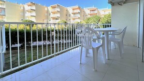 Un balcó amb caires blanques, cadires i taula, i vista cap a edificis d'apartaments.
