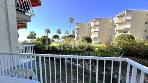 Un balcó amb barana blanca, amb vista a una zona residencial amb diversos edificis d'apartaments i palmeres.