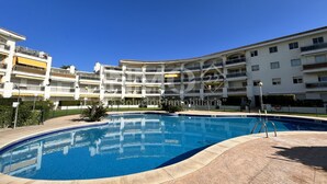 Una piscina rodeada por un edificio residencial de varios pisos con balcones.