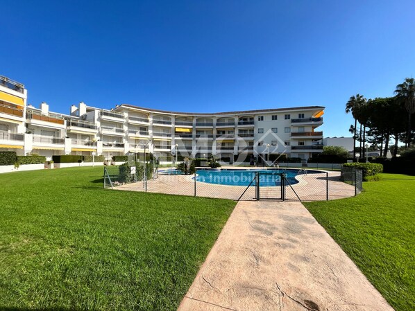 Un edificio residencial de varios pisos con una piscina en el centro.