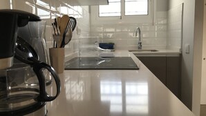 A modern kitchen with a coffee maker, utensils, and a sink. - Estudio Reformado Regueral - 123A (Cambrils)
