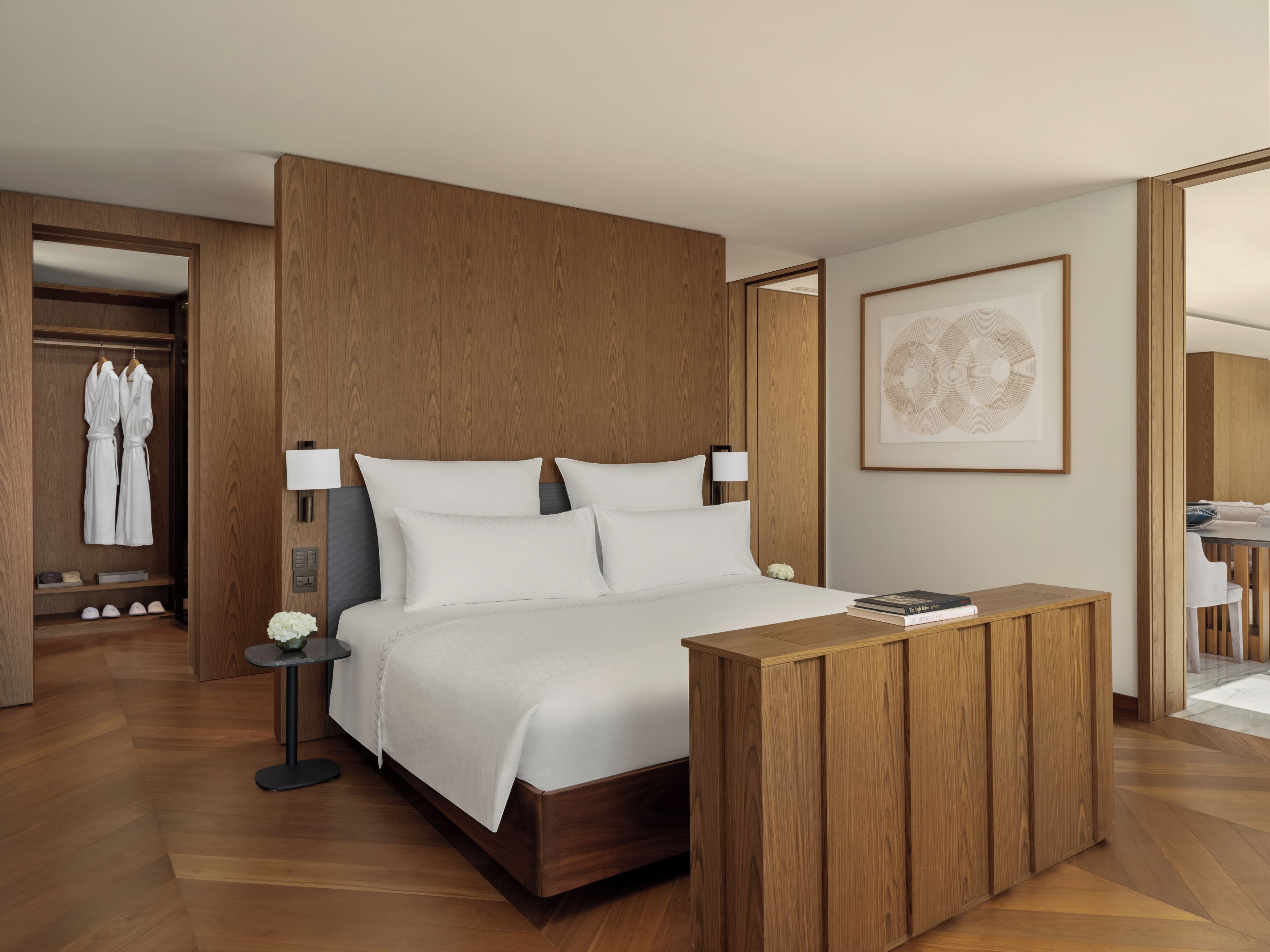 Una habitación de hotel moderna con un cabecero de madera, una mesita de noche con lámpara y una obra de arte enmarcada en la pared.