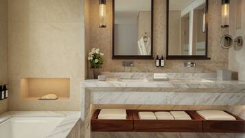 A modern bathroom with a marble vanity, dual mirrors, a built-in bench with towels, and a bathtub.