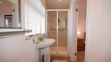 Baño con lavamanos, espejo y ducha.