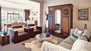 Ein Wohnzimmer mit einem braunen Ledersofa, einem Glastisch und einer großen Holzkommode.