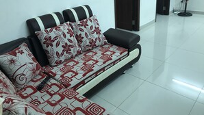 A sofa with patterned cushions in a room with a tiled floor and a door in the background. - Nancy Sweet Apartment (Ho Chi Minh City)