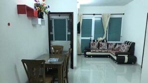 A dining area with a table and chairs, a sofa, and a window with curtains. - Nancy Sweet Apartment (Ho Chi Minh City)