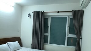 A bedroom with a bed, curtains, a window with blinds, and an air conditioning unit. - Nancy Sweet Apartment (Ho Chi Minh City)