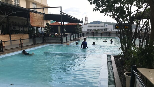 An outdoor swimming pool with tiled edges, surrounded by a metal railing. - Nancy Sweet Apartment (Ho Chi Minh City)
