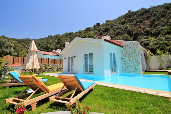 Una piscina al aire libre, sombrillas, sillones reclinables de piscina