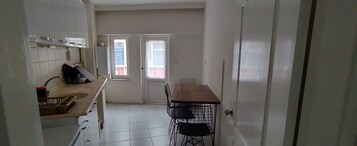 Una cocina compacta con armarios blancos, una encimera de madera y un comedor con mesa y sillas.