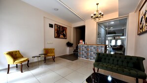 A spacious living area with a green sofa, yellow armchairs, and a marble coffee table. A chandelier hangs from the ceiling, and a painting adorns the wall. - Ada Kale Pansiyon (Çanakkale)