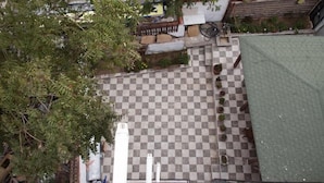 A courtyard with a checkered floor, potted plants, and a green roof. - Ada Kale Pansiyon (Çanakkale)