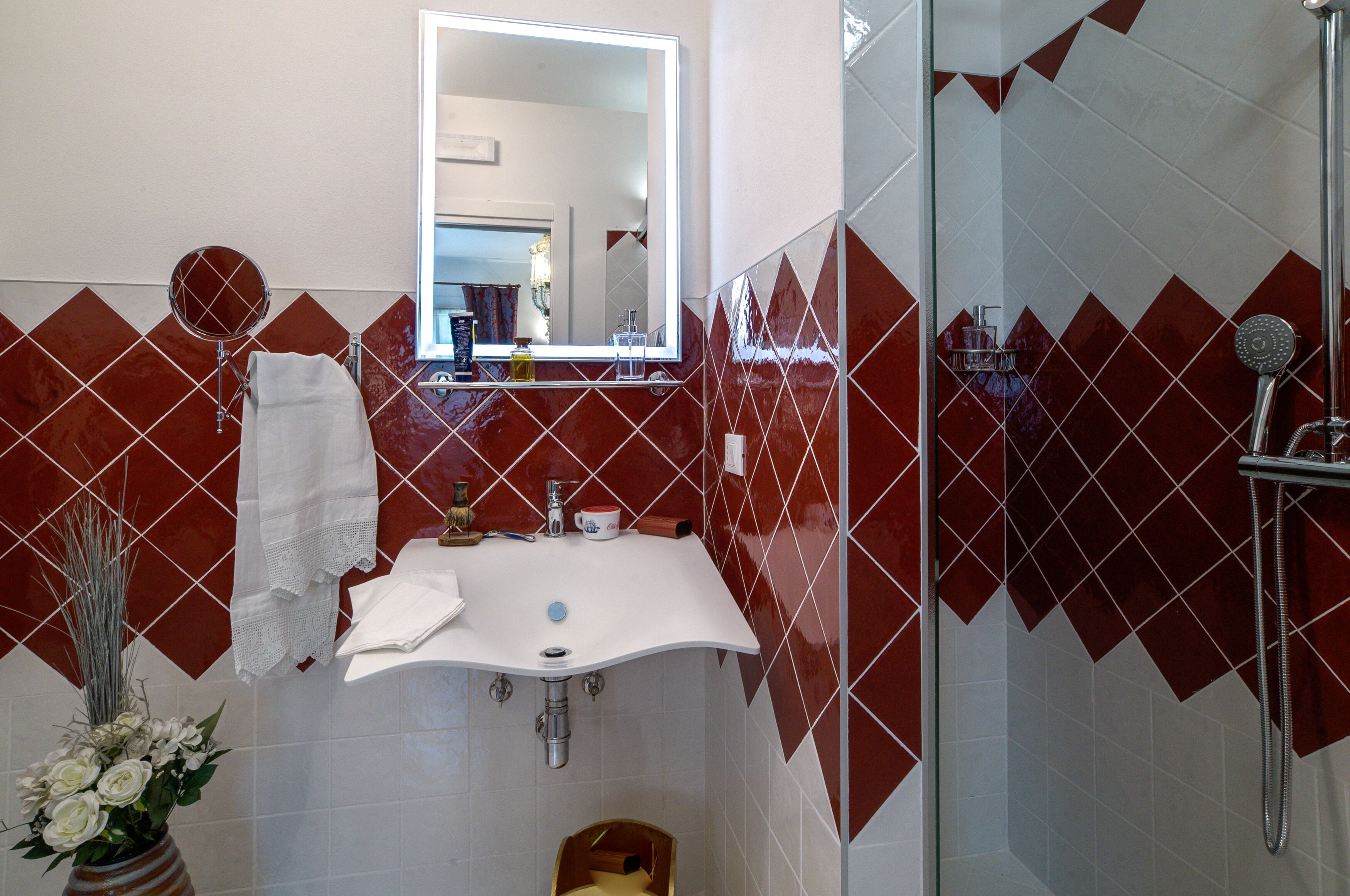 A bathroom with a white sink, mirror, and red-tiled walls.