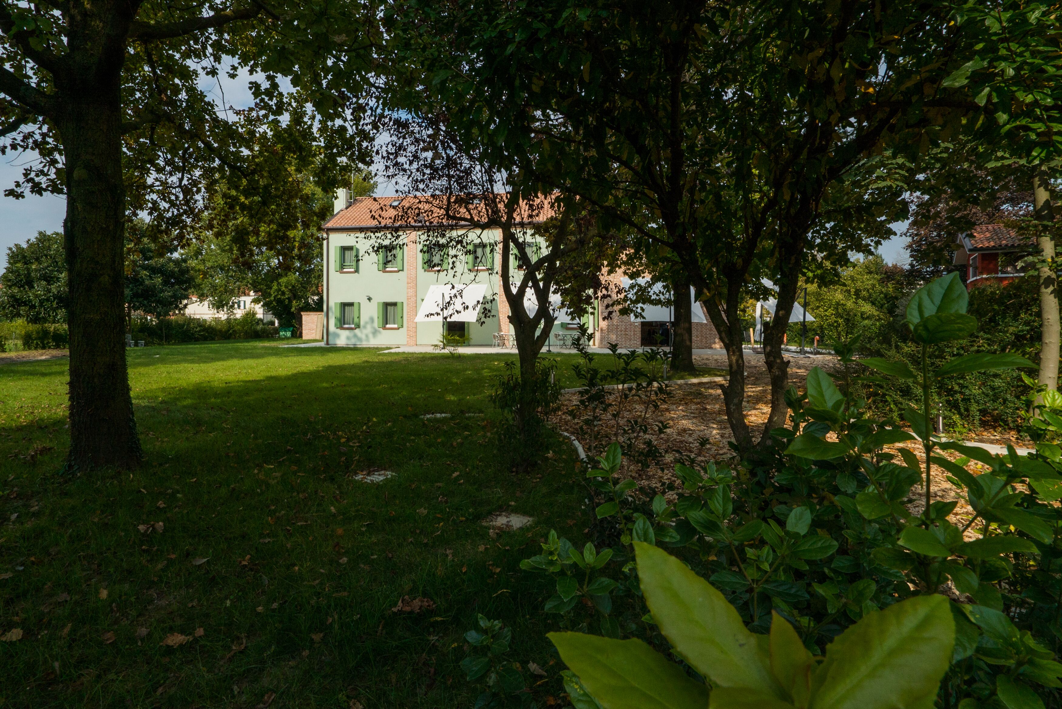 A building with a green lawn and trees in the foreground.
