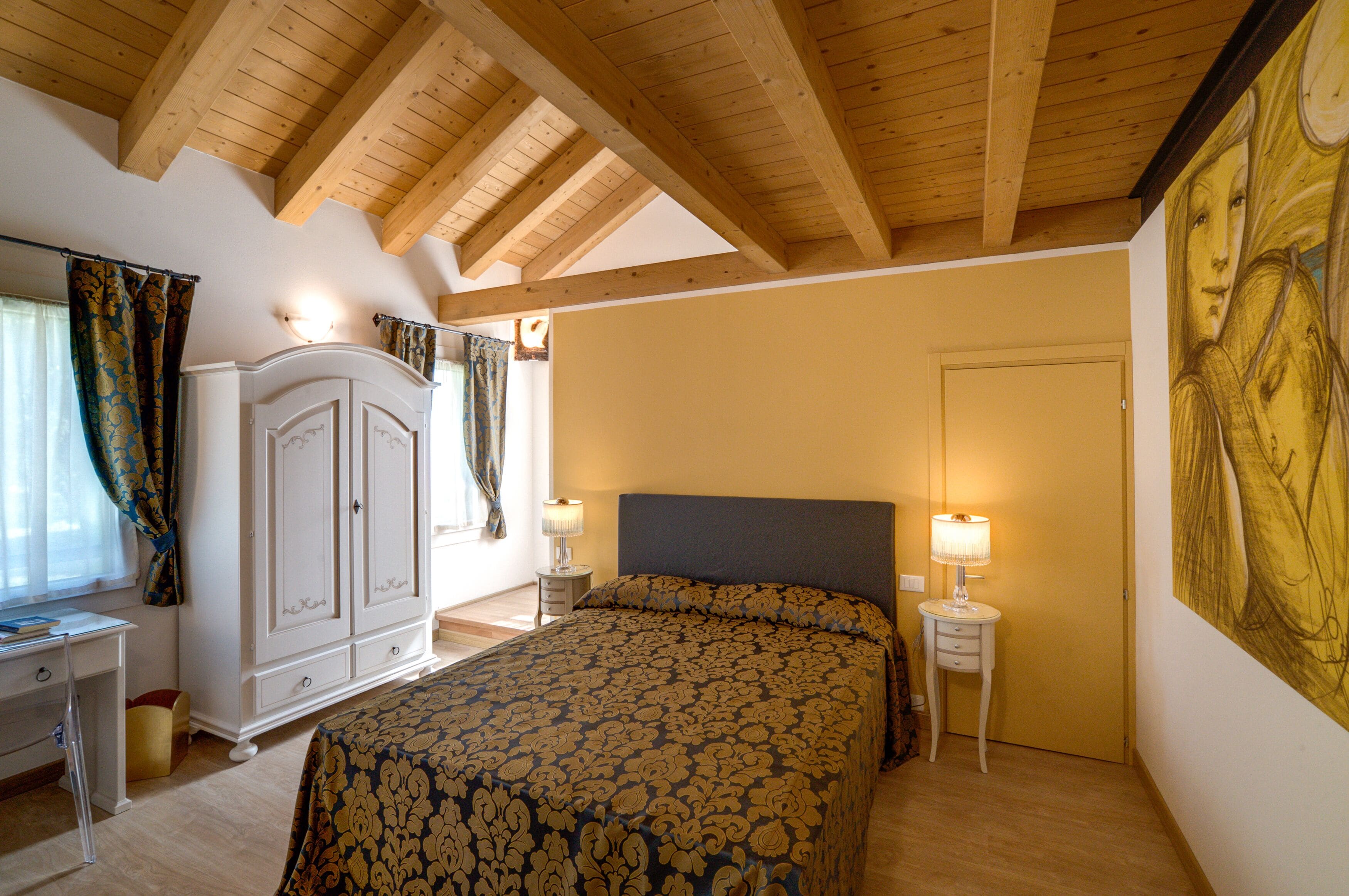 A bedroom with a bed, a wardrobe, a desk, and a painting on the wall.