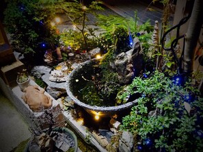 A garden with a pond, rocks, and various plants.