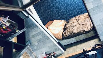 A compact room with a bed, a small table, and a chair.