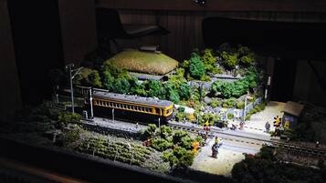 A model train layout with a train station, tracks, and surrounding greenery.