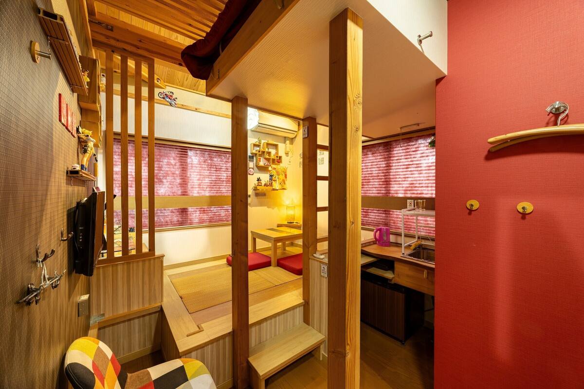 A traditional Japanese-style room with tatami flooring, a low wooden table, a bench, and a red wall.