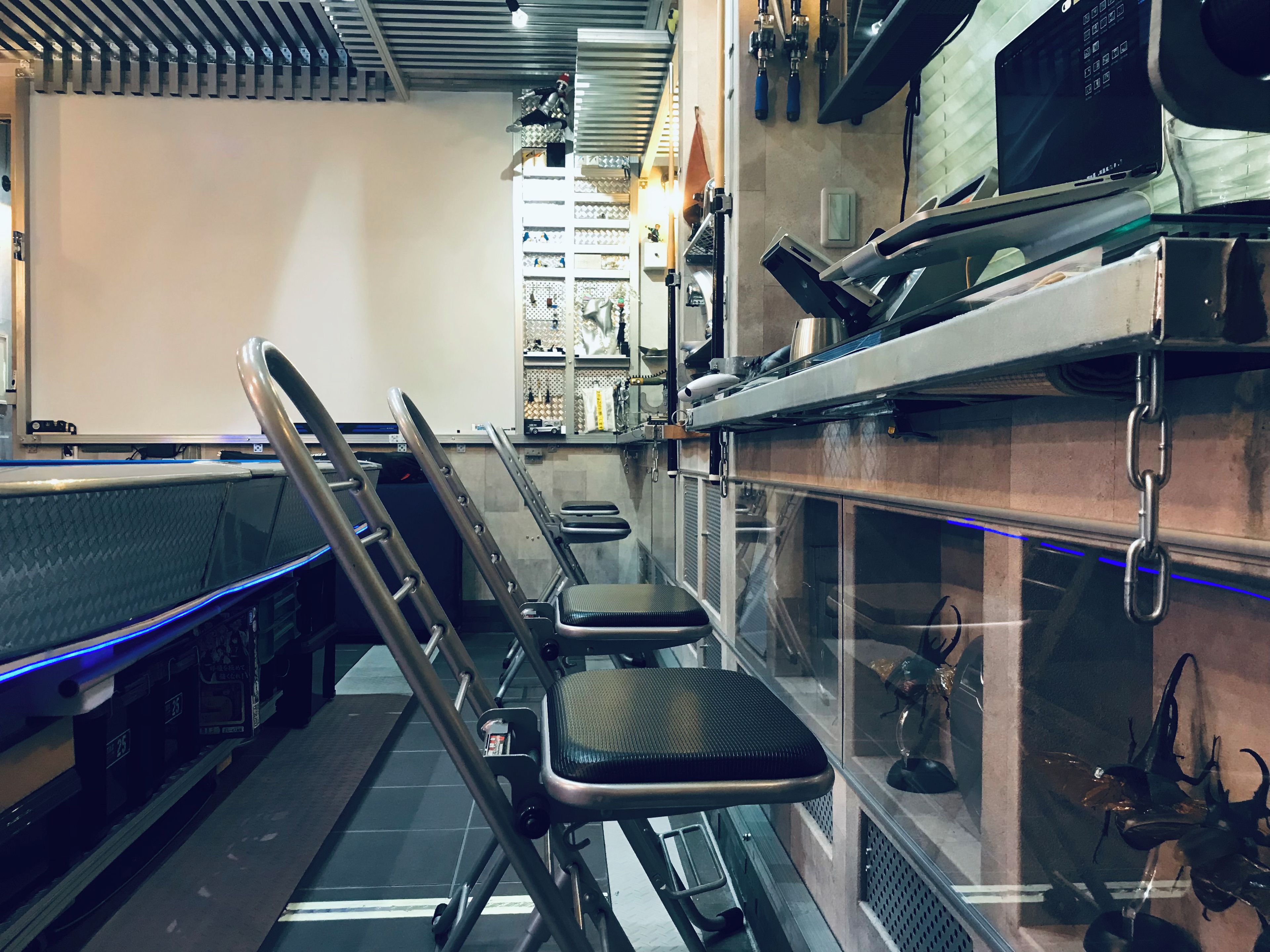 A modern kitchen with stainless steel appliances, a glass partition, and a seating area with chairs and a bench.