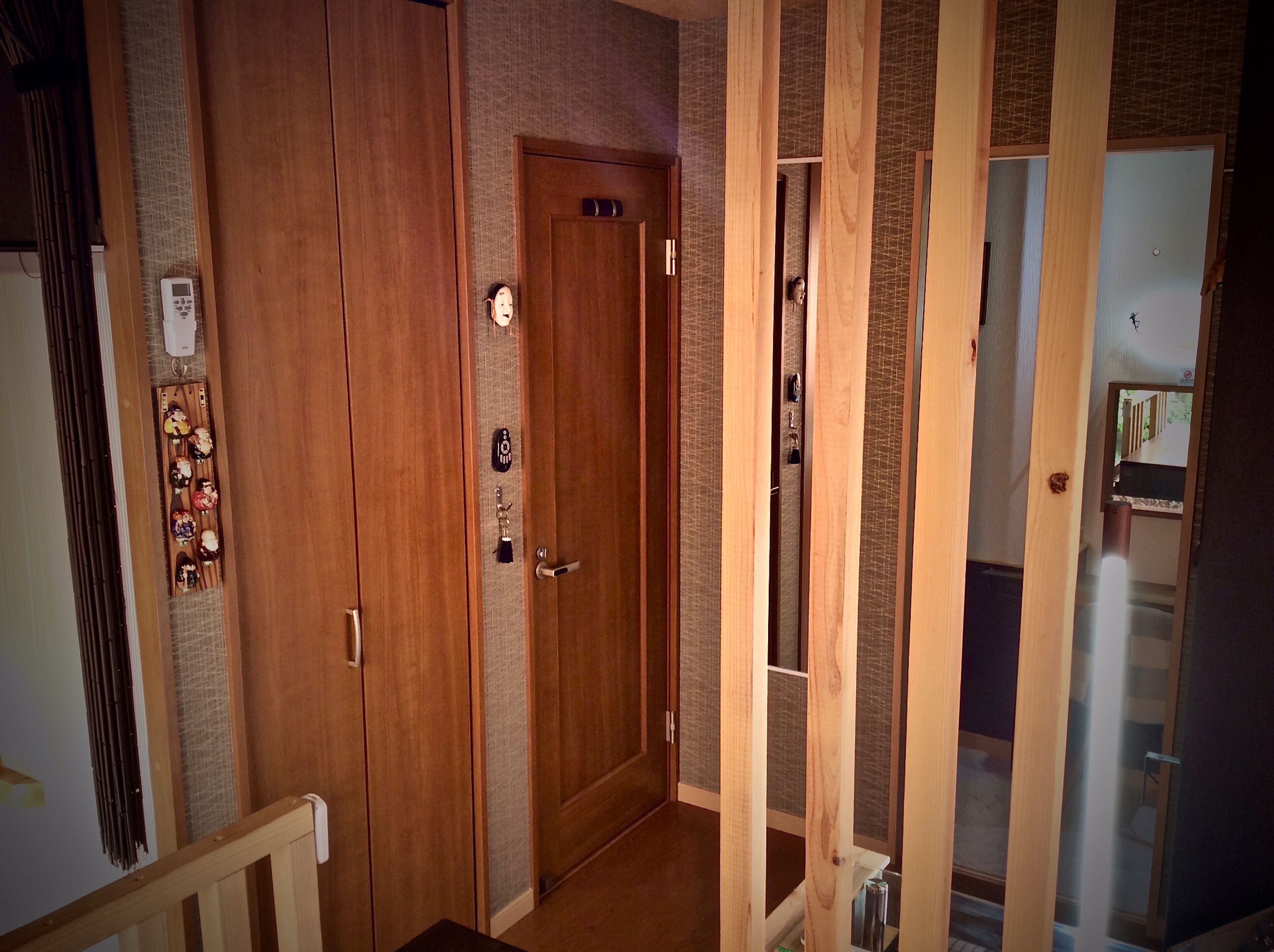 A wooden door with a keyhole and a lock, a small keychain with a key, and a wall-mounted thermostat.