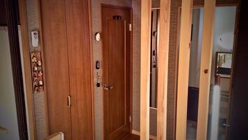 A wooden door with a keyhole and a lock, a small keychain with a key, and a wall-mounted thermostat.