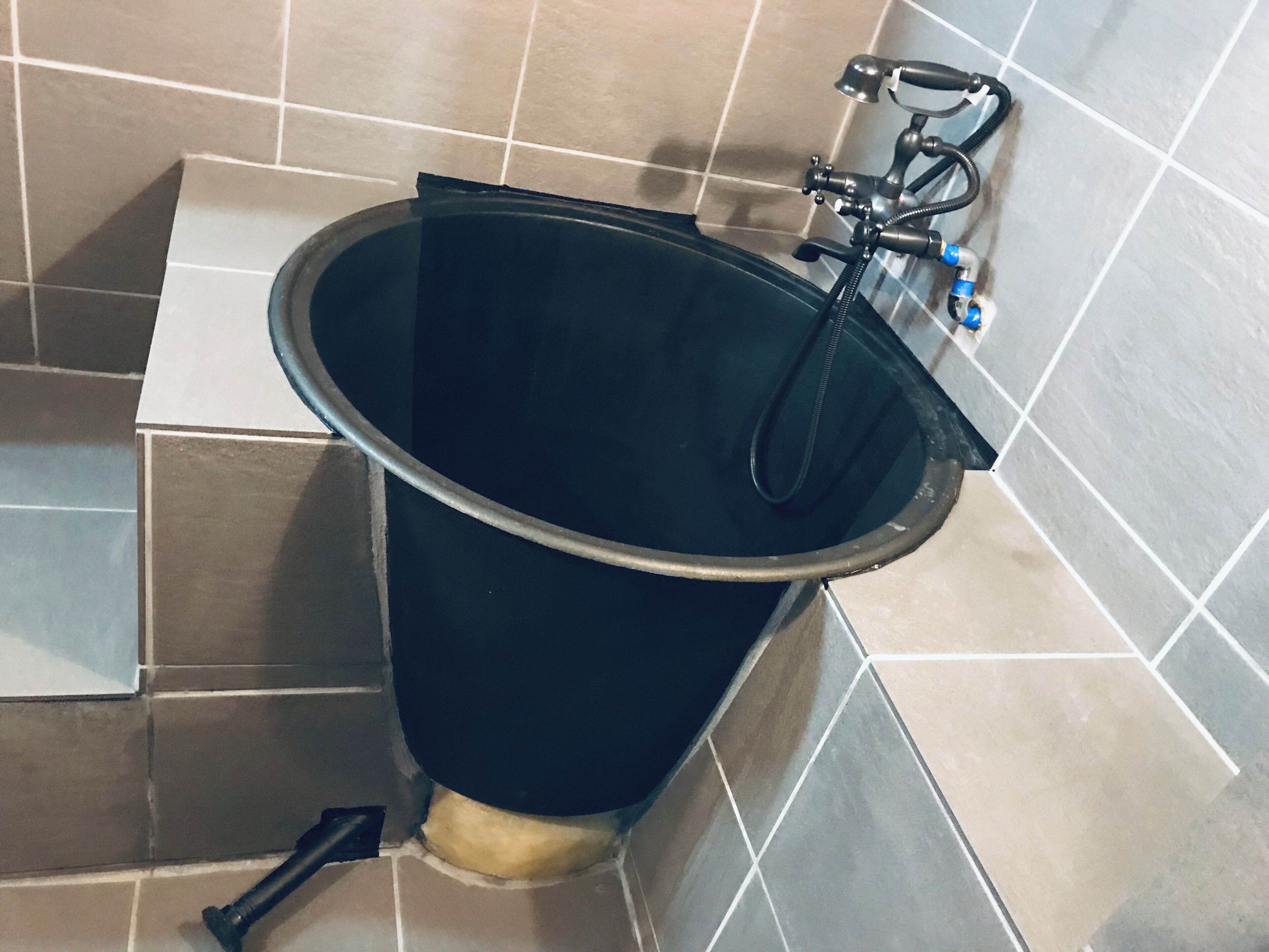 A bathroom with a black bathtub, a handheld showerhead, and a faucet.