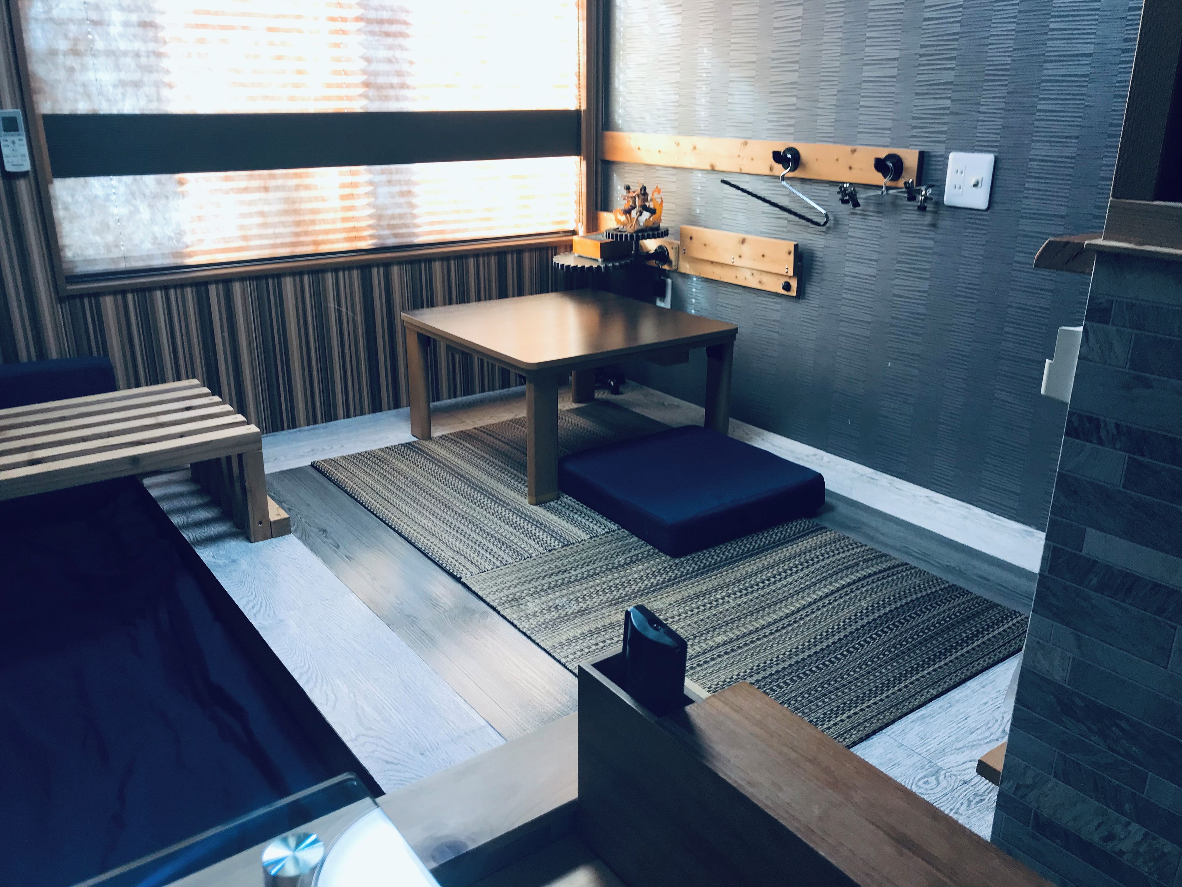 Una habitación moderna con un banco de madera, una mesa y un estante fijado a la pared con una cámara.