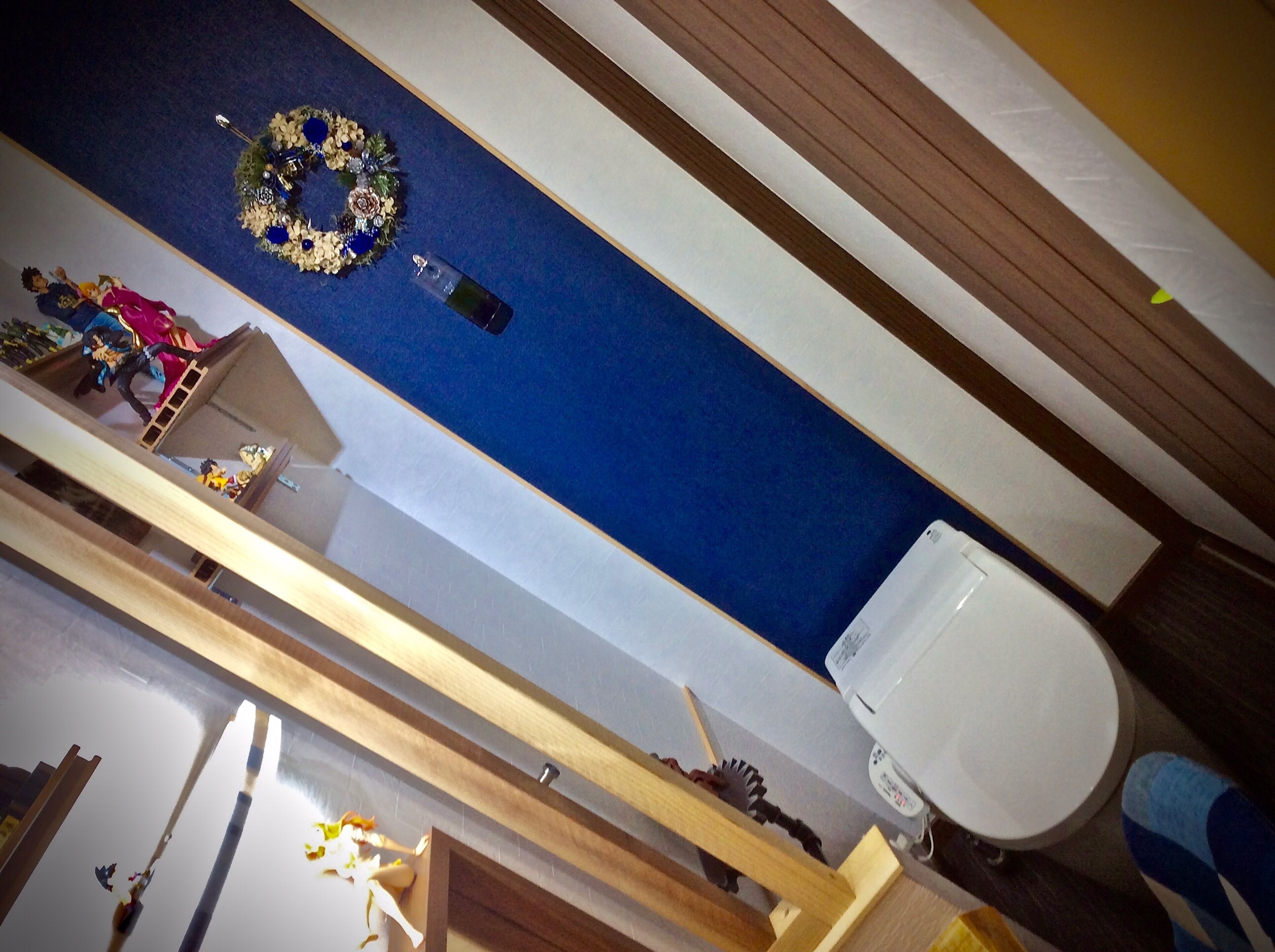 A room with a blue carpet, a white toilet, a wooden bench, and a small table with a decorative item.