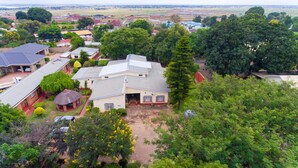 A residential area with houses, a thatched-roof structure, and surrounding greenery. - Nelly's Guesthouse (Lilongwe)