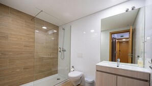 A modern bathroom with a glass-enclosed shower, a toilet, and a vanity with a mirror. - Central Suites 3 (Sao Joao da Madeira)