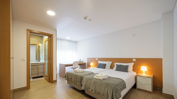 A hotel room with a double bed, bedside tables, a desk, and a mirror. - Central Suites 3 (Sao Joao da Madeira)