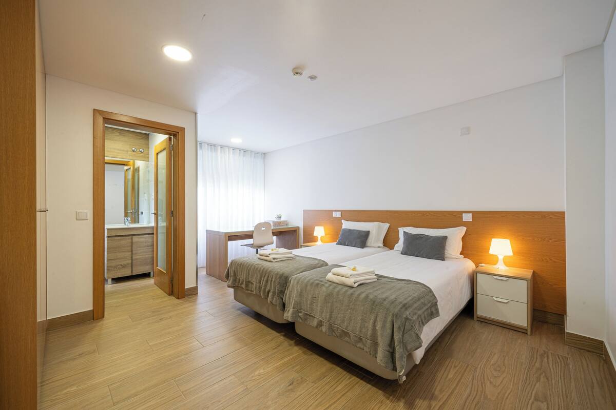 Una habitación de hotel con cama doble, mesitas de noche, un escritorio y un espejo.