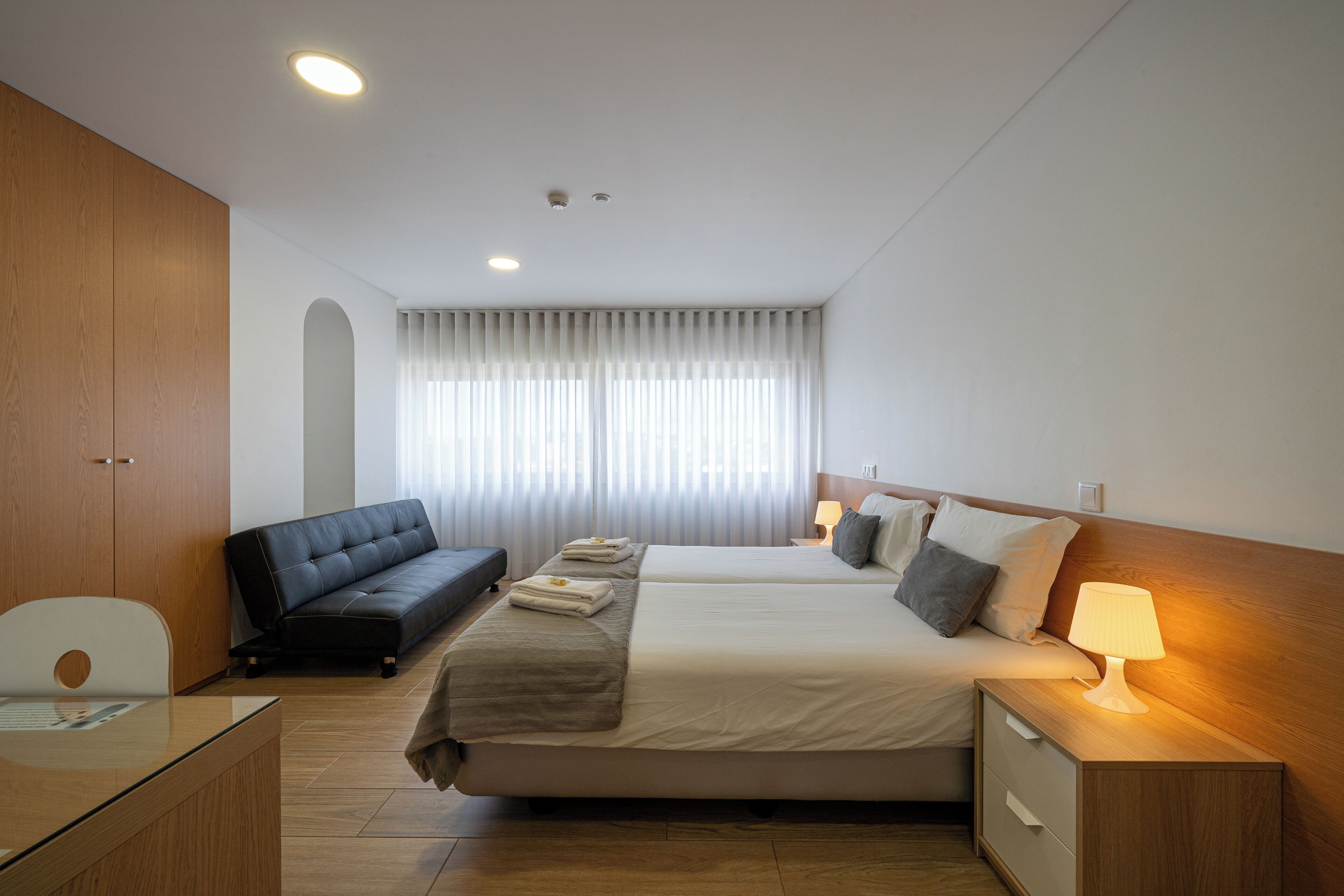 Una habitación de hotel con cama, sofá, escritorio y mesita de noche con lámpara.