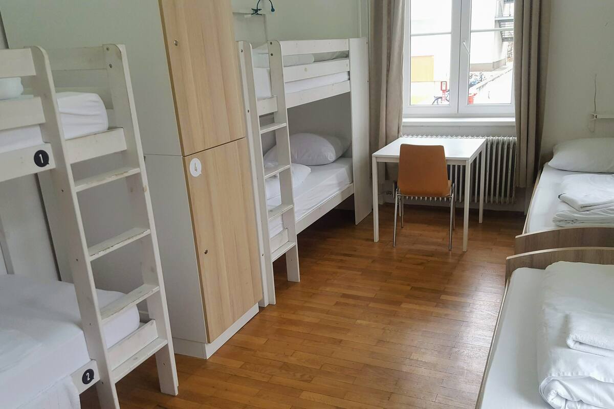 Ein Schlafsaalzimmer mit Etagenbetten, einem Schreibtisch und einem Stuhl.